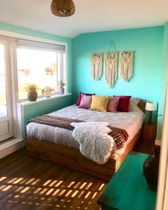 a bedroom with a bed with blue walls and a window at Costa Linda B&B in Vlissingen