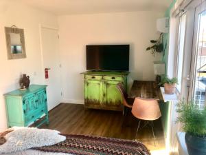 a living room with a green dresser with a television at Costa Linda B&B in Vlissingen