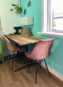 una mesa de madera con 2 sillas rosas en una habitación en Costa Linda B&B, en Vlissingen