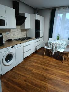a kitchen with white cabinets and a table with chairs at Apartament 55m2 for you in Szczawno-Zdrój