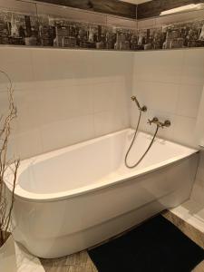uma banheira branca com um chuveiro na casa de banho em Apartament 55m2 for you em Szczawno-Zdrój