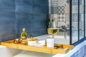 a wooden tray with a glass of wine on a bath tub at La Cour de l'Opera - PrestiPlace Tours in Tours