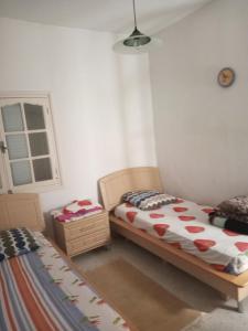 1 dormitorio con 2 camas y ventana en Maison de vacances, en Tabarka