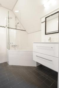 een witte badkamer met een wastafel en een douche bij Hotel In den Brouwery in Domburg