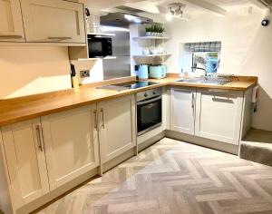 uma cozinha com armários brancos e piso em madeira em Hideaway Cottage em Barnoldswick