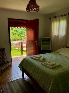 una camera da letto con un letto e due asciugamani di Pousada Pinho Verde a Monte Verde