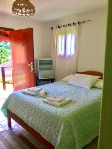 una camera da letto con un letto e asciugamani di Pousada Pinho Verde a Monte Verde