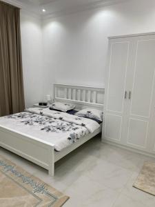 a white bedroom with a bed and a cabinet at Jabal Masfut Villa استراحة جبل مصفوت in Sharīyah