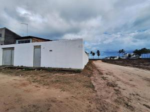 a white building on the side of a dirt road at Casa de Avinha in Sirinhaém