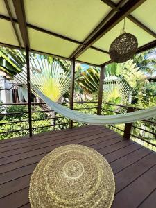 a table and a hammock on a wooden deck at La reserve villa tropicana in Pipa