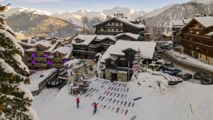 two people skiing in the snow in front of a lodge at Le Lana in Courchevel