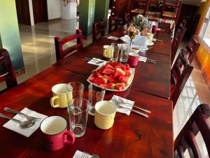 - une longue table en bois avec une assiette de fruits dans l'établissement AVANI HOSPEDAJE, à Lligua
