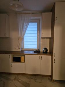 a kitchen with a window and a microwave at Apartament Milanówek in Milanówek +8 photos