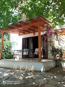 patio ze stołem i krzesłami pod pergolą w obiekcie Katerina's SeaSide w mieście Afissos