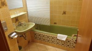 a bathroom with a sink and a green bath tub at Hotel Waldhaus in Bodenmais +149 photos