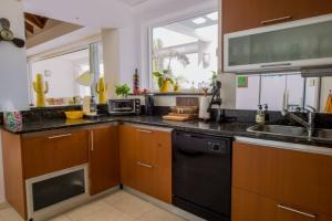 a kitchen with wooden cabinets and a black dishwasher at Villa Jambalaya in Maho Reef