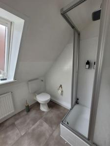 uma casa de banho branca com um WC e um chuveiro em Watt´ne Bude in Büsum em Büsum