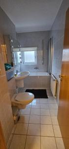 uma casa de banho com um WC, um lavatório e uma banheira em An apartment located at nature with 2.5 rooms em Dusseldorf