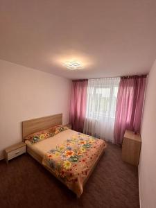 Schlafzimmer mit einem Bett und einem Fenster mit rosa Vorhängen in der Unterkunft Apartament 2 camere Sector 1 in Bukarest