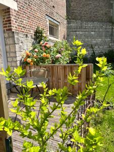 um deque de madeira com uma mesa, um banco e flores em La Parenthese du Rond Royal em Compiègne