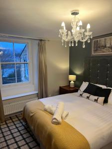 a bedroom with a bed with a chandelier and a window at The Railway Hotel in Haydon Bridge