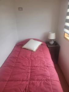 Una cama con una manta rosa y una almohada. en Maravilloso departamento en el sur de Chile, en La Unión