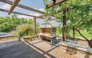 a wooden deck with a stone grill in a yard at Villa & Ferienwohnung Rosa in Stari Pazin