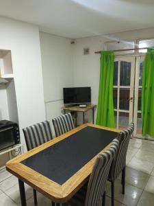 ein Esszimmer mit einem Tisch und grünen Vorhängen in der Unterkunft alojamiento la pipi in Las Heras