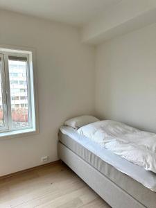 a bed in a white room with a window at Nydelig perle rett ved fjorden in Sandnes