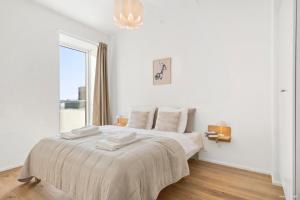 ein weißes Schlafzimmer mit einem großen Bett und einem Fenster in der Unterkunft Spacious waterfront apartment with marina and sea view in Arhus