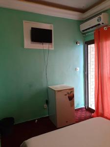 a room with a green wall with a refrigerator and a television at HOTEL KEUTCHA in Douala