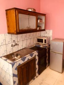 a small kitchen with a sink and a refrigerator at HOTEL KEUTCHA in Douala