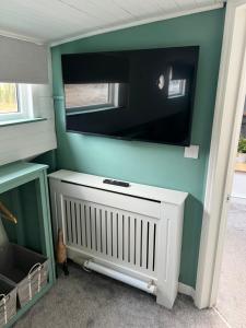 a tv on the wall of a room with a radiator at Judith Barge in Colchester