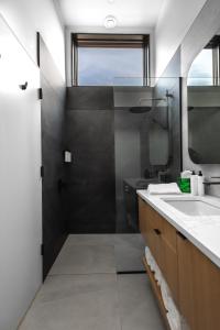 a bathroom with a shower and a sink and a mirror at Spruce - Luxury 1 Bdrm Cottage Stunning Views & Hot Tub, Private Path to the Beach in Margaree Harbour
