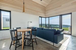 a living room with a blue couch and a table at Spruce - Luxury 1 Bdrm Cottage Stunning Views & Hot Tub, Private Path to the Beach in Margaree Harbour