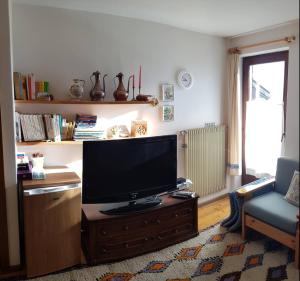 sala de estar con TV de pantalla plana en un centro de entretenimiento de madera en Appartamento Pepe en Castello di Fiemme