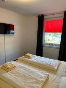 a bedroom with two beds and a window with a red blind at Residenz Mühlenberg Typ A in Willingen +2 photos