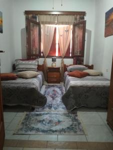a bedroom with three beds and a window with curtains at Old House in Paradeísion