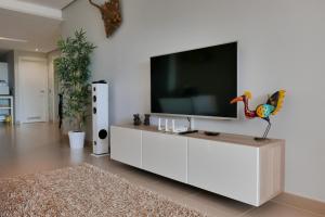ラ・カラ・デ・ミハスにあるCasa La Floristaの白いキャビネット上のテレビ付きのリビングルーム