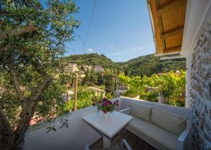balcón con sofá blanco y mesa con flores en Bungalow nefeli en Agios Gordios