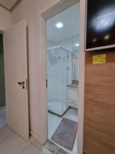 een badkamer met een douche en een glazen deur bij Apartamento FRENTE PARA 0 MAR - PÉ NA AREIA - 3 SUITES COM AR CONDICIONADO, 2- VAGAS DE GARAGEM - FINAMENTE DECORADO - PRAIA DO MORRO-INTERNET -WI-FI -TV COM SERVIÇOS DE DISNEY PLUS - NETFLIX -HBO MAX -STAR MAX - JOGOS AMAZON FIRE STICK - ALEXIA in Guarapari