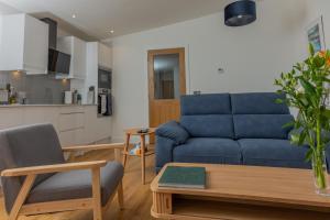 a living room with a blue couch and a kitchen at Rowan Cottage in Kensaleyre