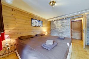 Cama grande en habitación con pared de madera en Magnifique et Chaleureux Chalet à Val d'Isere en Le Fornet