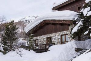 een met sneeuw bedekte hut met een met sneeuw bedekt dak bij Magnifique et Chaleureux Chalet à Val d'Isere in Le Fornet