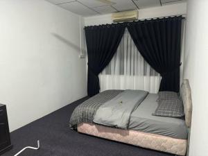 een bed in een kamer met een raam met gordijnen bij Erma Homestay Kota Bharu in Kota Bharu