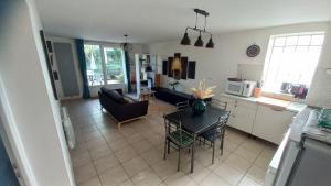 eine Küche und ein Wohnzimmer mit einem Tisch und Stühlen in der Unterkunft Plaisir des prés - Appartement T3, jardin, parking in Chaponost