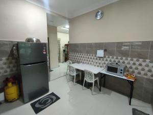 een keuken met een koelkast en een tafel met stoelen bij Zahani Homestay in Kuala Terengganu