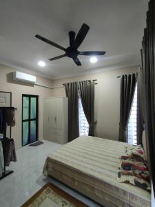 een slaapkamer met een bed en een plafondventilator bij Zahani Homestay in Kuala Terengganu