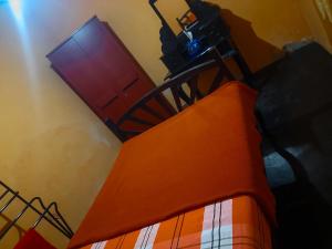 a room with a bed with an orange blanket and a door at Hill House Haldummulla in Badulla