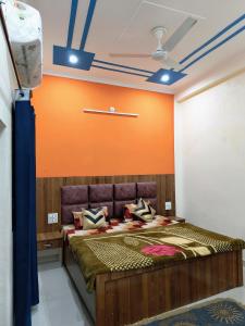 a bedroom with a large bed with an orange wall at SHREE JI HOMESTAY in Rishīkesh